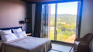 A hotel room with a large bed, a chair, and a view of a green landscape through a large window. - Villa Croix Valmer / Gigaro, air-conditioned, beach on foot with heated swimming pool (La Croix-Valmer)