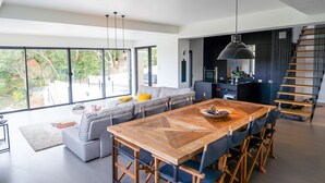 A modern kitchen with a large wooden table, grey sofa, and a staircase. - Villa Croix Valmer / Gigaro, air-conditioned, beach on foot with heated swimming pool (La Croix-Valmer)