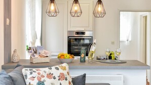 Een moderne keuken met een centraal eiland, hanglampen en een eethoek met een bloemenkussen.