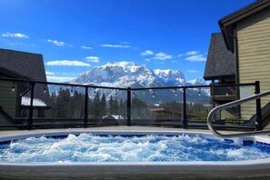Un bain à remous avec vue sur les montagnes, entouré de bâtiments.