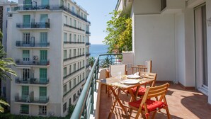 Un balcón con mesa y sillas, con vistas a la ciudad y al mar.