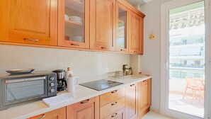 Una cocina con armarios de madera, un tostador, una cafetera y un balcón con puerta corrediza de vidrio.
