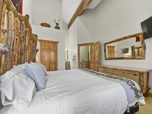 Cozy retreat with a large bed, wooden headboard, dresser, and wardrobe.
