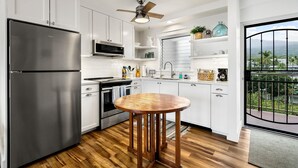 Une cuisine moderne avec des meubles blancs, des appareils en acier inoxydable et une table à manger en bois.