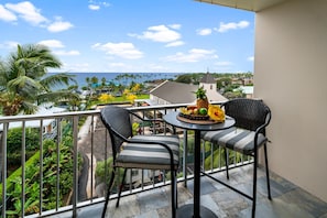 Enjoy a tranquil view from this balcony with a table and two chairs.