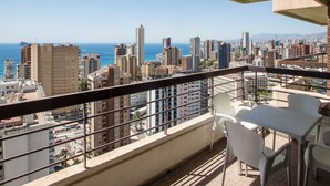 Un balcon offrant une vue sur le paysage urbain et l’océan.