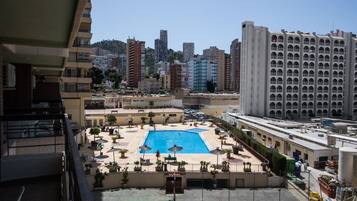 Une piscine sur le toit, entourée d’espaces de détente et avec une vue sur le paysage urbain en arrière-plan.
