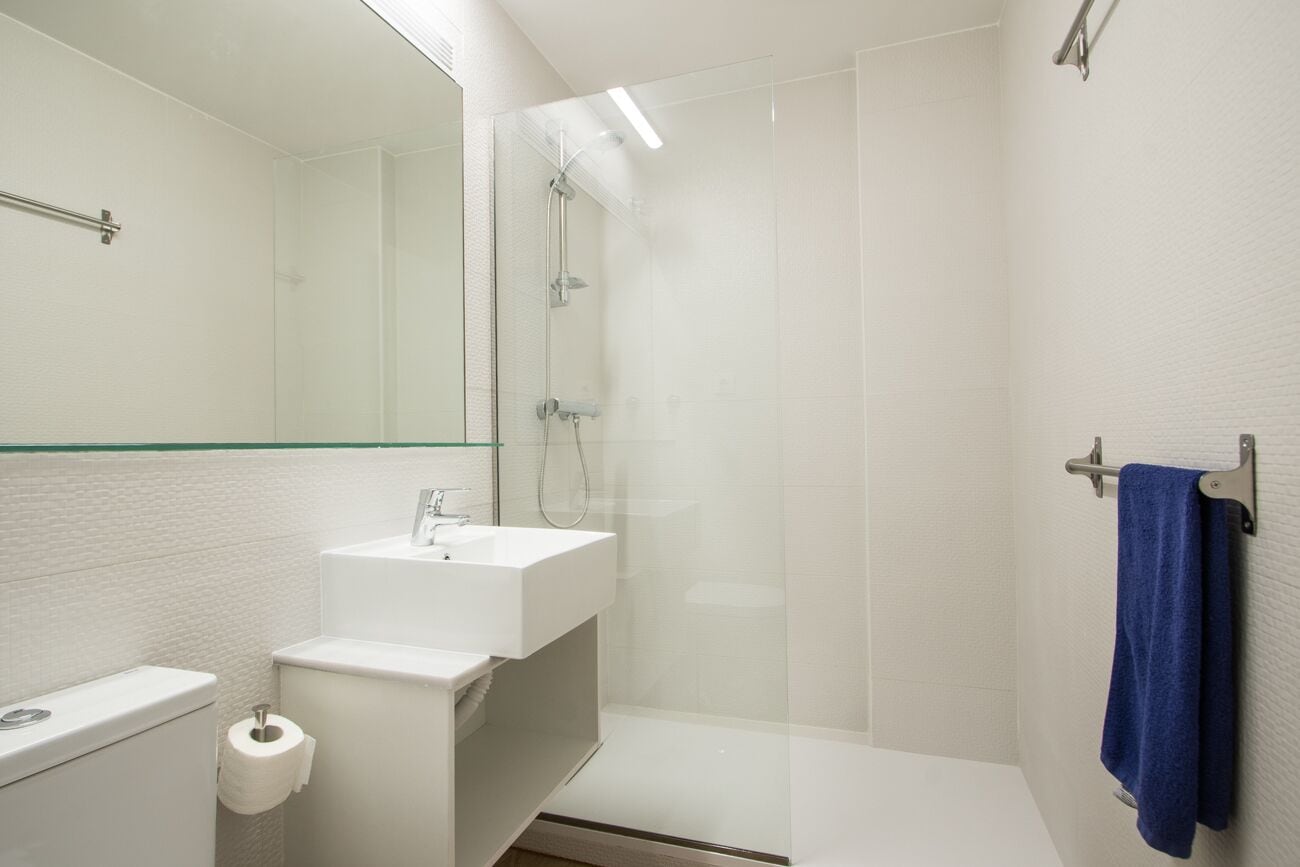 A modern bathroom with a glass shower enclosure, a white sink, and a toilet.