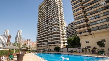 A high-rise residential building with a swimming pool area.