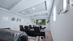 A home theater room with a flat-screen TV, reclining chairs, and a carpeted floor. - Upscale Villa with Home Theater at Reunion (Kissimmee)