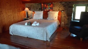 Um quarto aconchegante com uma cama grande, paredes de madeira, uma parede de destaque em pedra e uma obra de arte colorida.