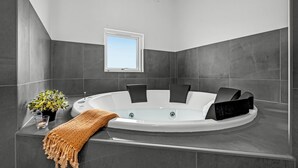 Een moderne badkamer met een vrijstaand bad, een raam en een plant in pot.