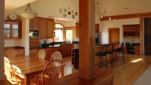 Un'ampia cucina con mobili in legno, una grande isola con sgabelli da bar e un'area pranzo con sedie.