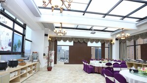 A spacious room with a high ceiling and large windows, featuring a long table set for dining with purple chairs and a view of the cityscape. - Melody Hotel (Longyan)