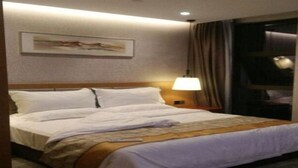 A hotel room with a neatly made bed, a bedside lamp, a framed picture on the wall, and a window with curtains. - Melody Hotel (Longyan)