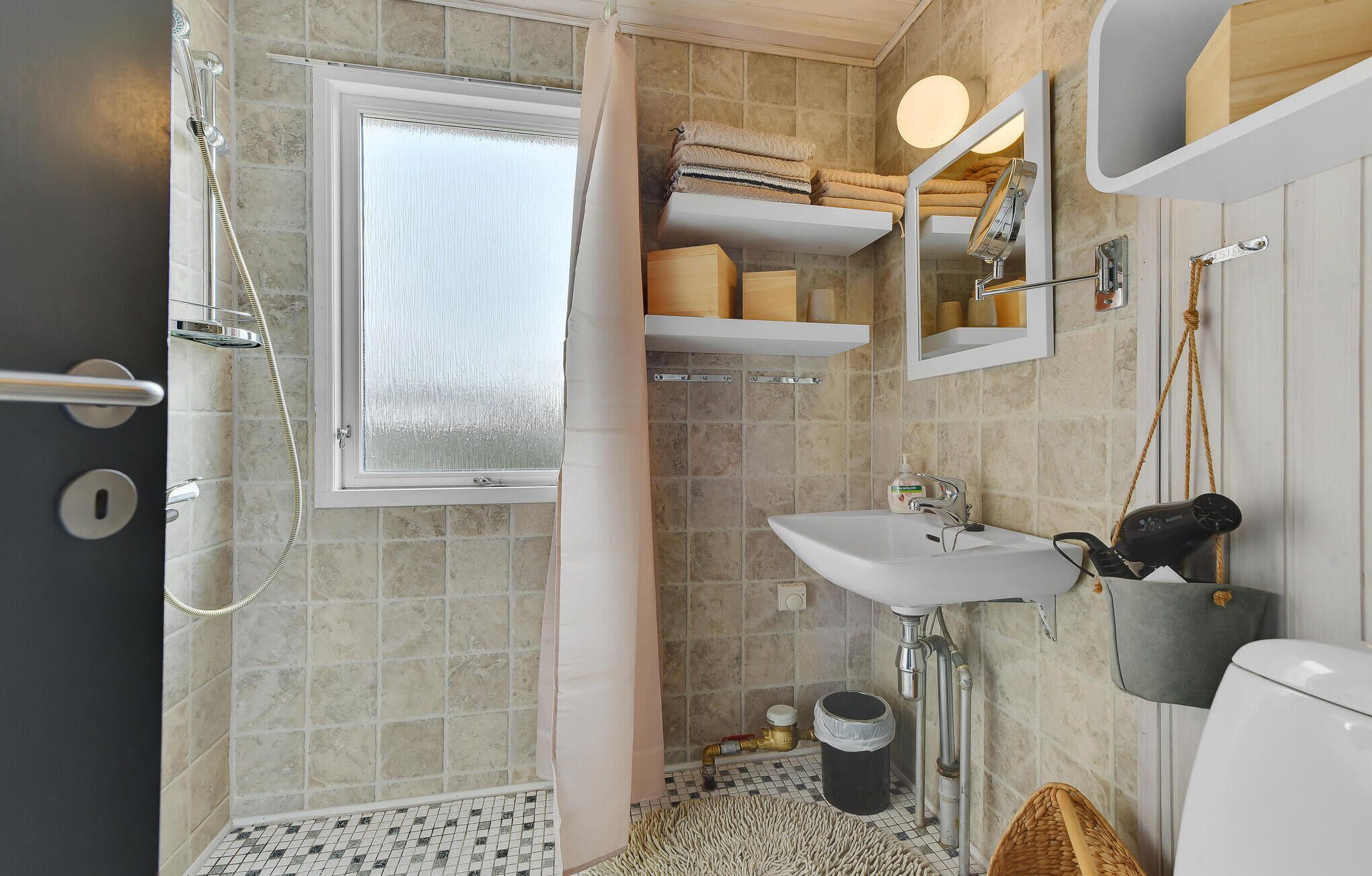 Ein Badezimmer mit Dusche, Waschbecken, Toilette und Fenster.