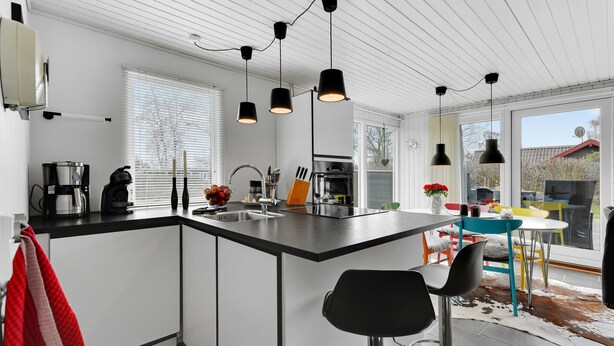 A modern kitchen with a central island, black pendant lights, a coffee maker, and a sink. - 3 bedroom beautiful home in Sydals (Sydals)