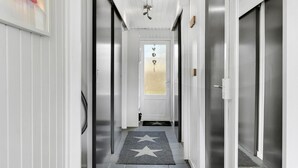 A narrow hallway with white walls and doors, a star-patterned rug, and a frosted glass door at the end. - 3 bedroom beautiful home in Sydals (Sydals)