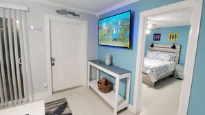 A bedroom with a bed, a nightstand, a TV, and a console table with decorative items.