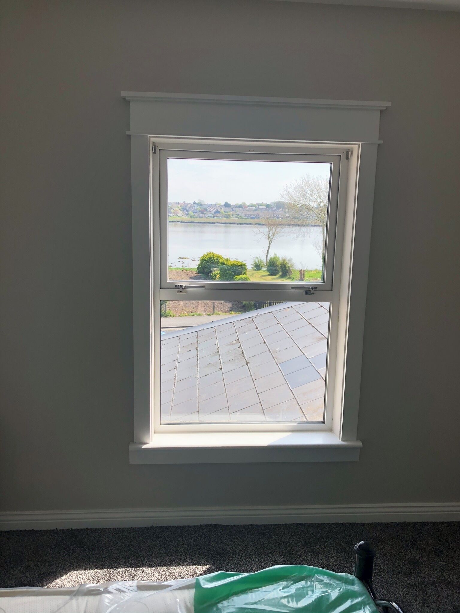 Ein Zimmer mit Fensterblick auf einen See und eine gepflasterte Fläche.