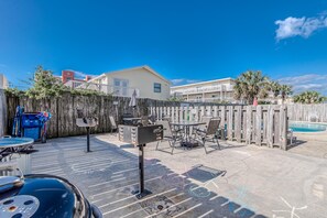 Enjoy al fresco dining and relaxation in our patio area, featuring a barbecue grill, dining table, and poolside seating.