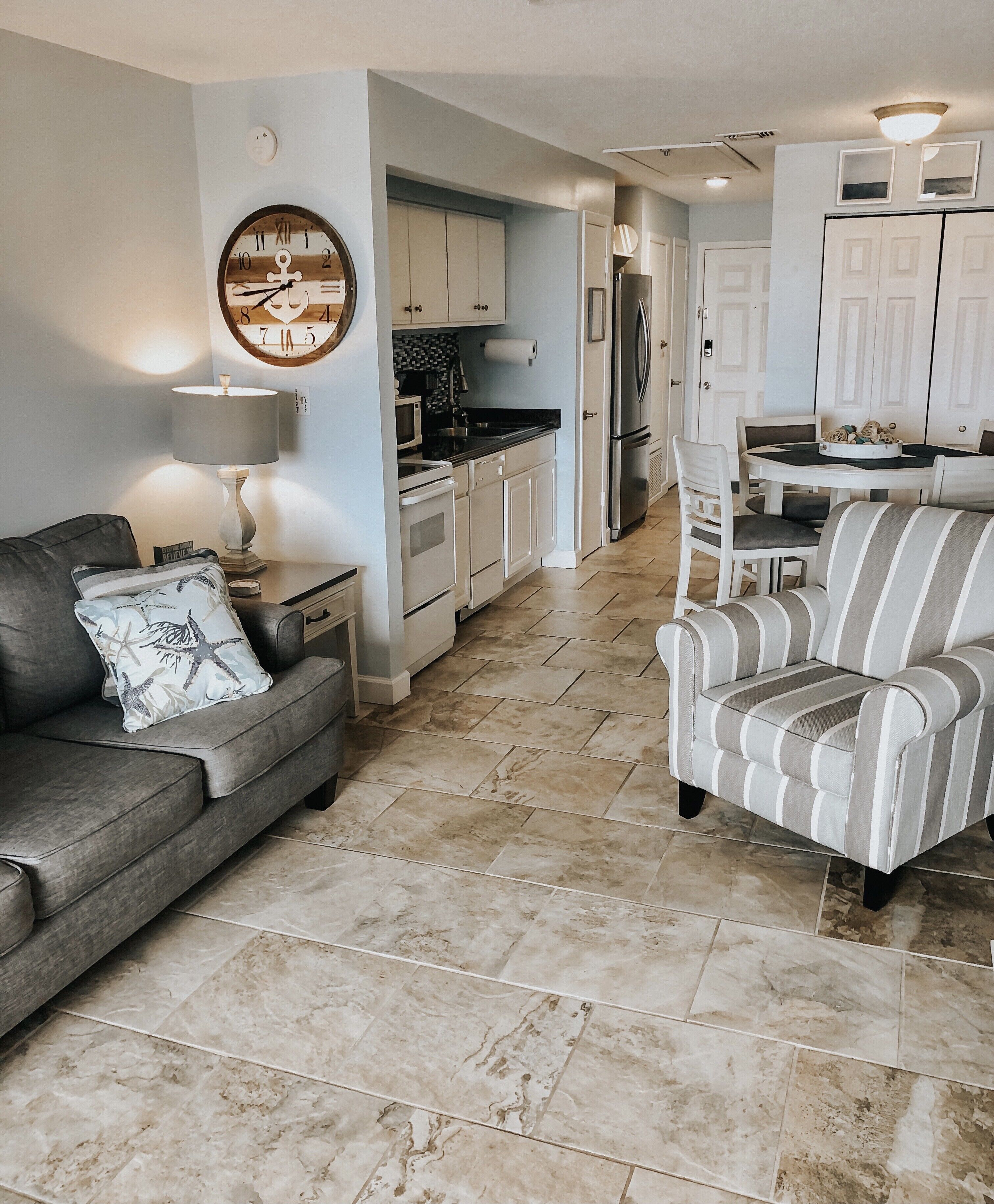 A modern kitchen with white cabinets, a refrigerator, and a dining table with chairs.