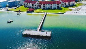 An aerial view of a coastal hotel with a dock extending into the water, surrounded by buildings with red roofs. - Footsteps away from beautiful beaches 🏖🏝⛱ (Navarre)