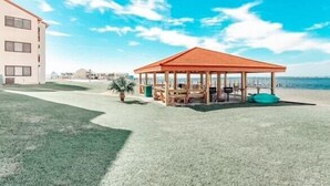 A beachside gazebo with a tiled roof, a grassy area, and a building in the background. - Footsteps away from beautiful beaches 🏖🏝⛱ (Navarre)