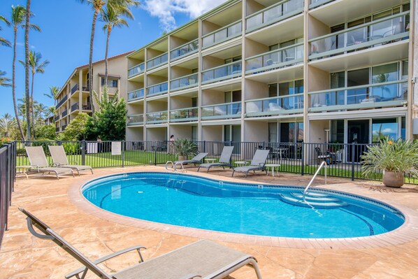 Un hotel con piscina, varios balcones y palmeras.