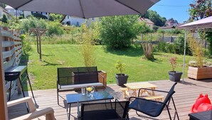 Un espace patio aménagé avec du mobilier d’extérieur, notamment une table et des chaises, placé sous un grand parasol.