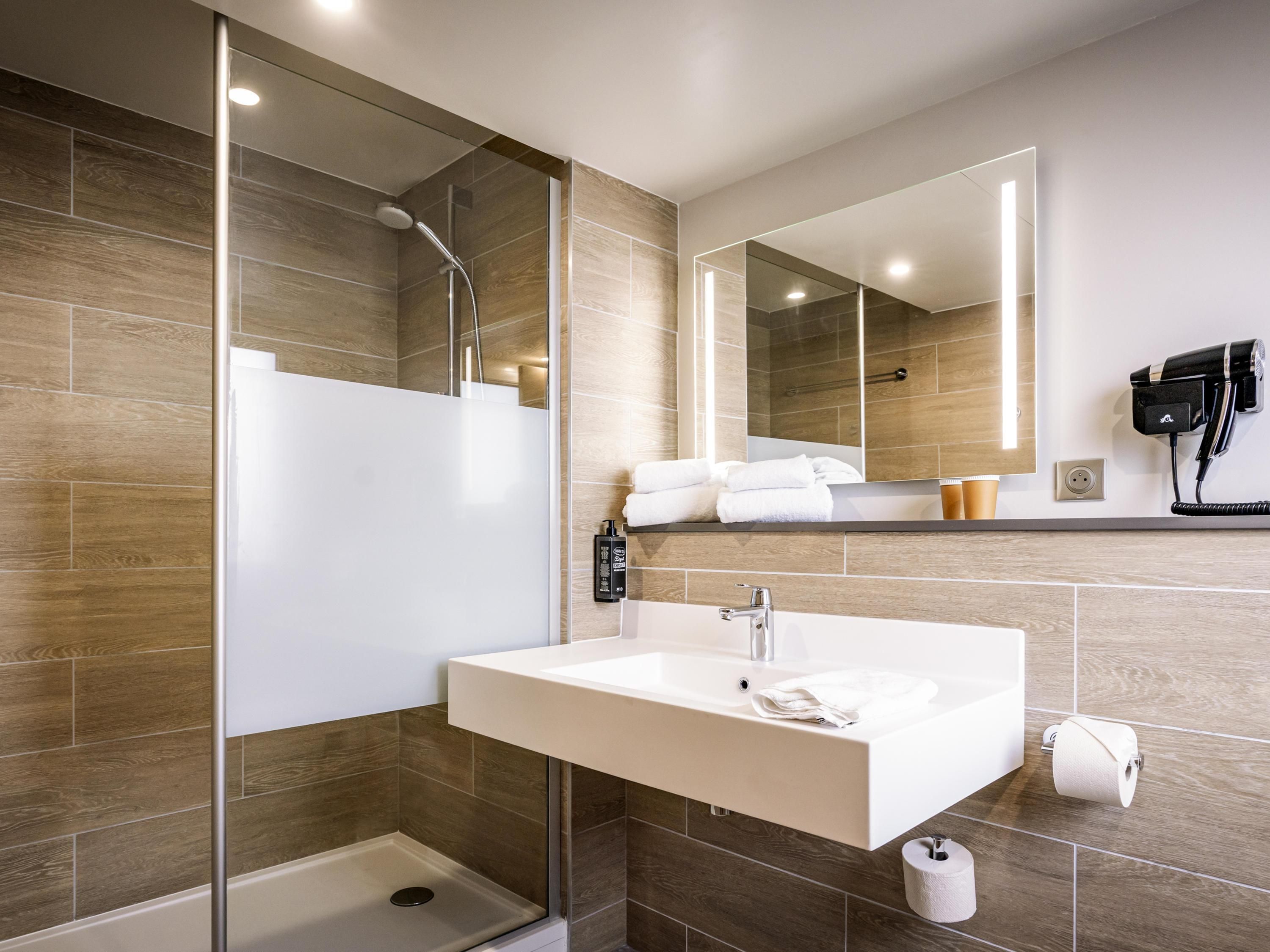 A modern bathroom with a shower, sink, and toilet.