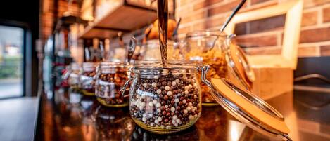 Una hilera de frascos de vidrio con tapas sobre una encimera, probablemente conteniendo salsas o aperitivos.