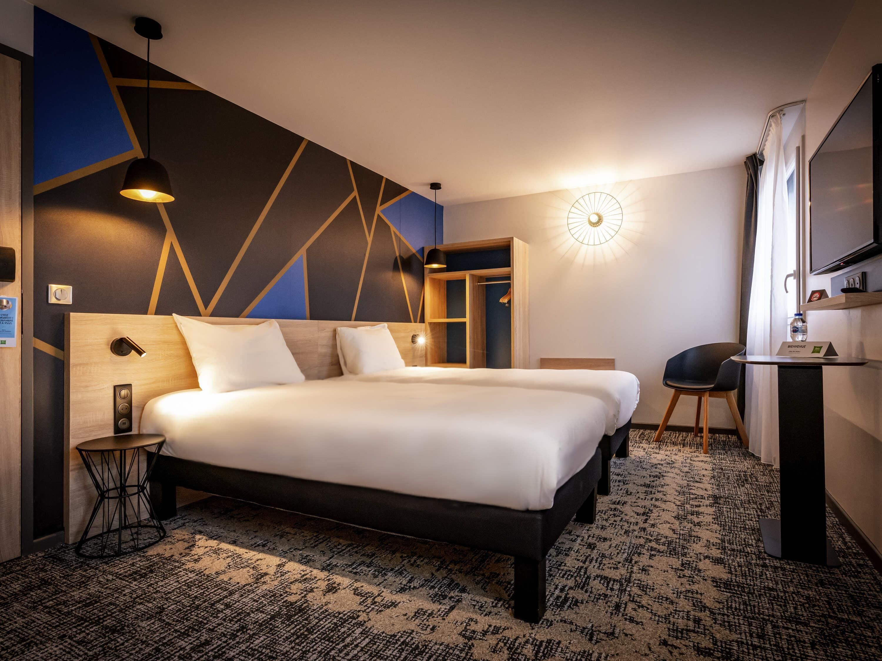 A hotel room with a large bed, bedside tables, a desk, and a mirror.