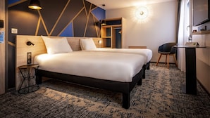 A hotel room with a large bed, bedside tables, a desk, and a mirror.