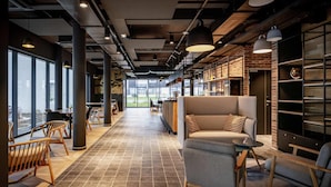 A modern interior with a long corridor, seating areas, and large windows.