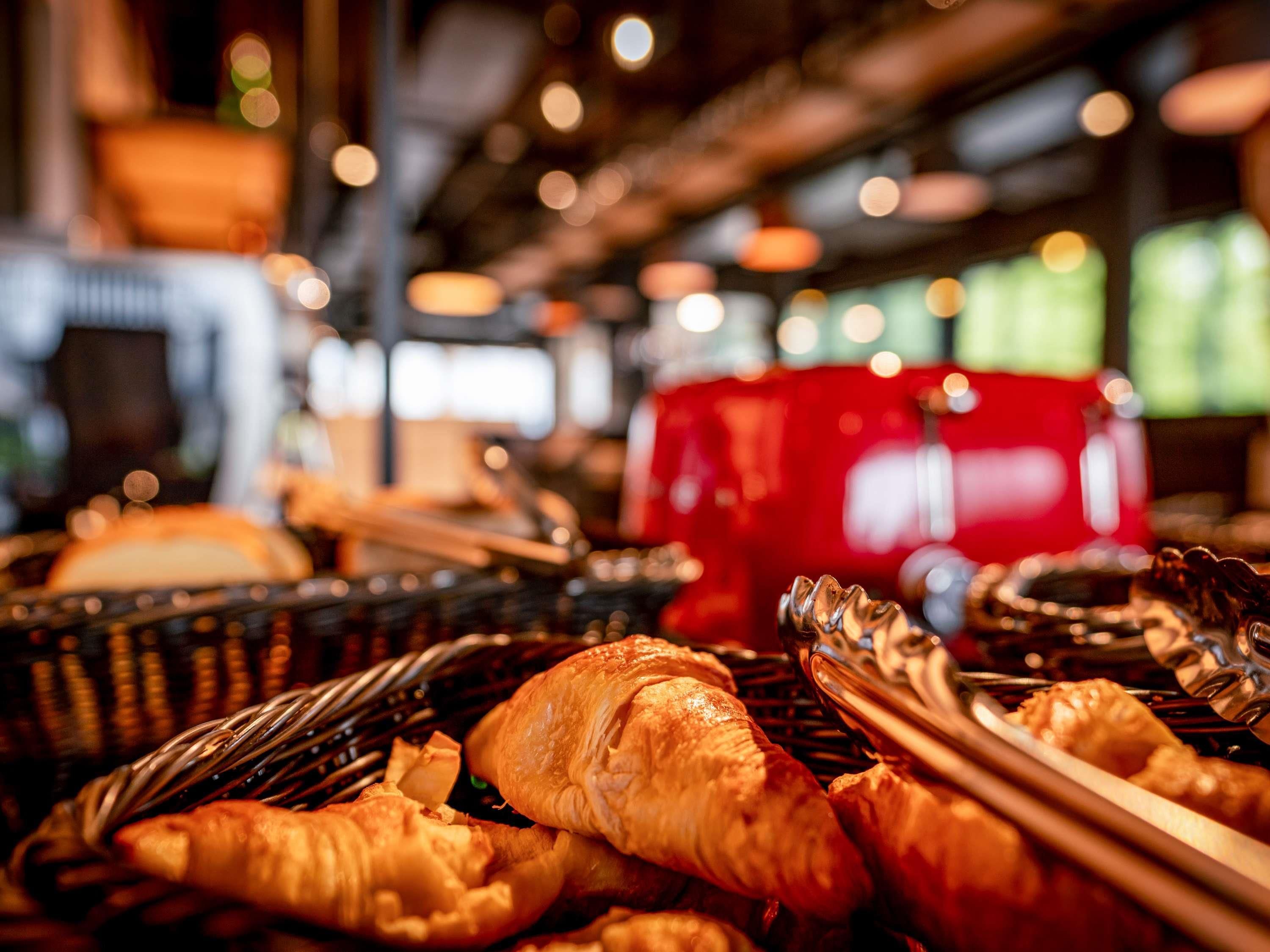 Ein reichhaltiges Buffet mit verschiedenen Speisen, darunter Croissants und Zangen, in einem gut beleuchteten Innenraum.