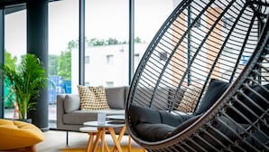 A modern interior with a hanging chair, sofa, and a small table.
