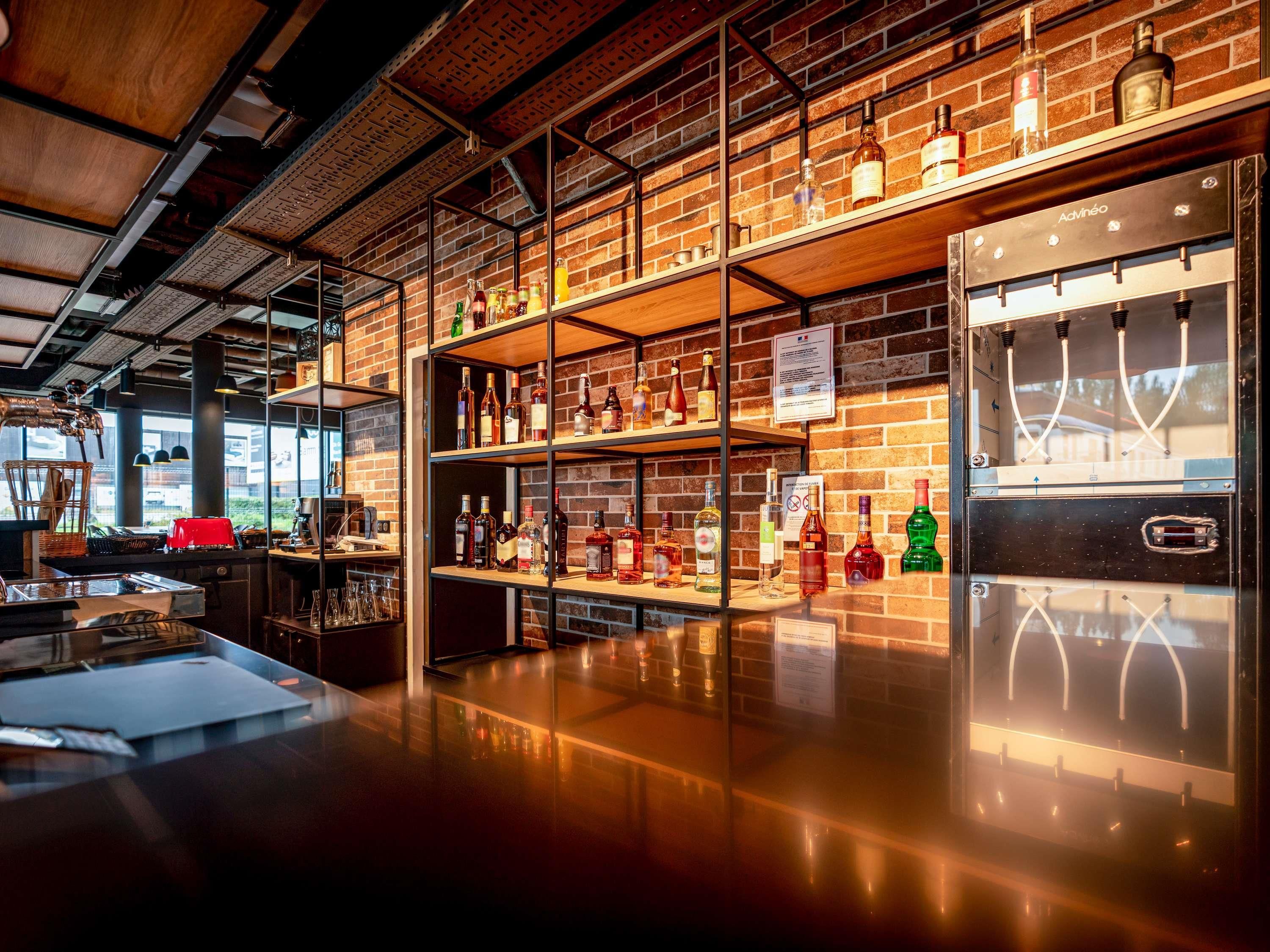 A bar area with shelves of liquor bottles, a counter with glasses, and a branded appliance.