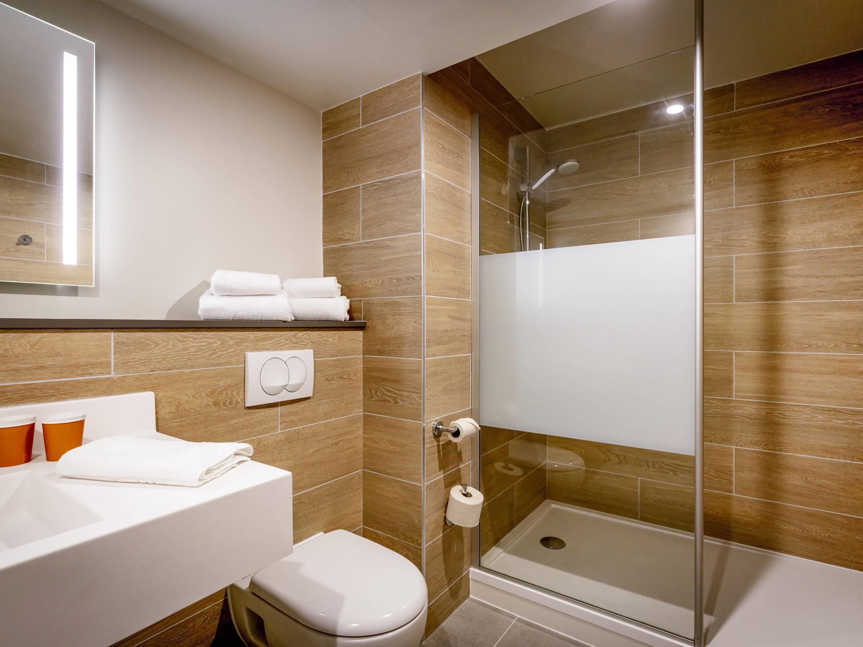 A modern bathroom with a shower, toilet, and sink.