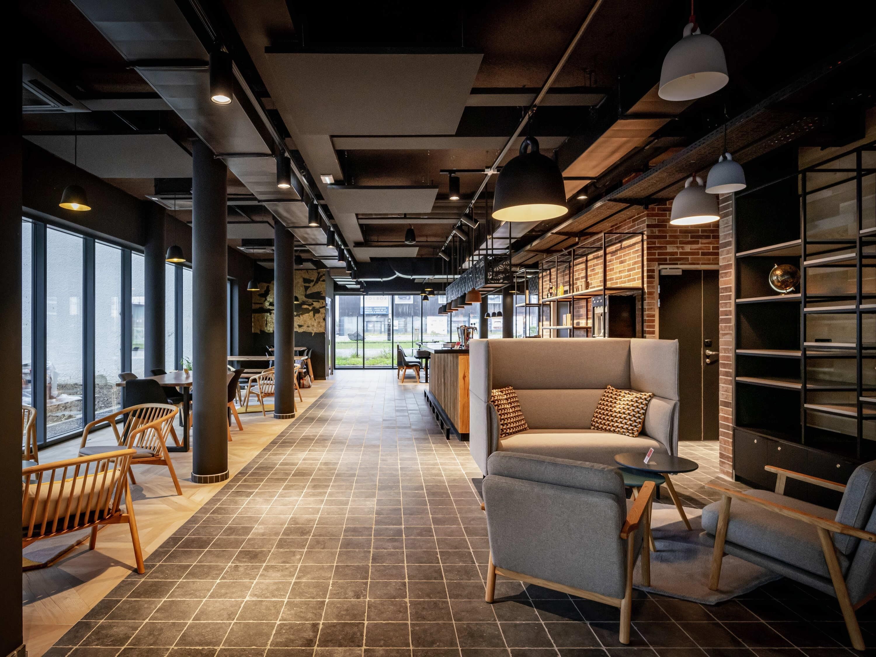 A modern interior with a long corridor, seating areas, and large windows.