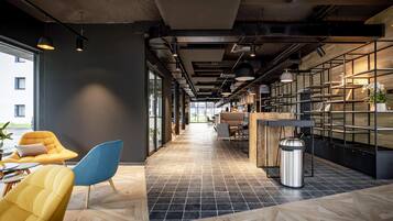 Un intérieur moderne avec un long couloir, des espaces de détente et un coin cuisine.