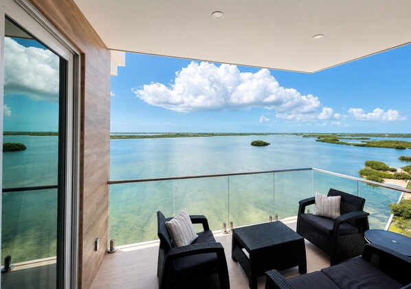 A balcony with a clear view of a tropical landscape, including water and greenery.