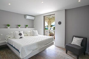 A modern bedroom with a bed, a chair, and a balcony view. - Sunrise 21 (Collectivité de Saint-Martin)