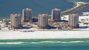 Un complejo hotelero frente al mar con varios edificios altos, una playa y arena.