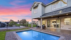 A modern house with a swimming pool, covered patio, and a view of the neighborhood. - Waterfront House | Heated Pool* | Pet Friendly (Horseshoe Bay)