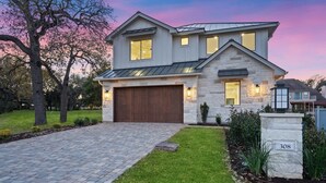 A modern two-story house with a stone facade, a large garage, and a well-maintained lawn. - Waterfront House | Heated Pool* | Pet Friendly (Horseshoe Bay)