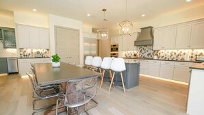 A modern kitchen with a central island, white cabinetry, and pendant lighting. - Waterfront House | Heated Pool* | Pet Friendly (Horseshoe Bay)