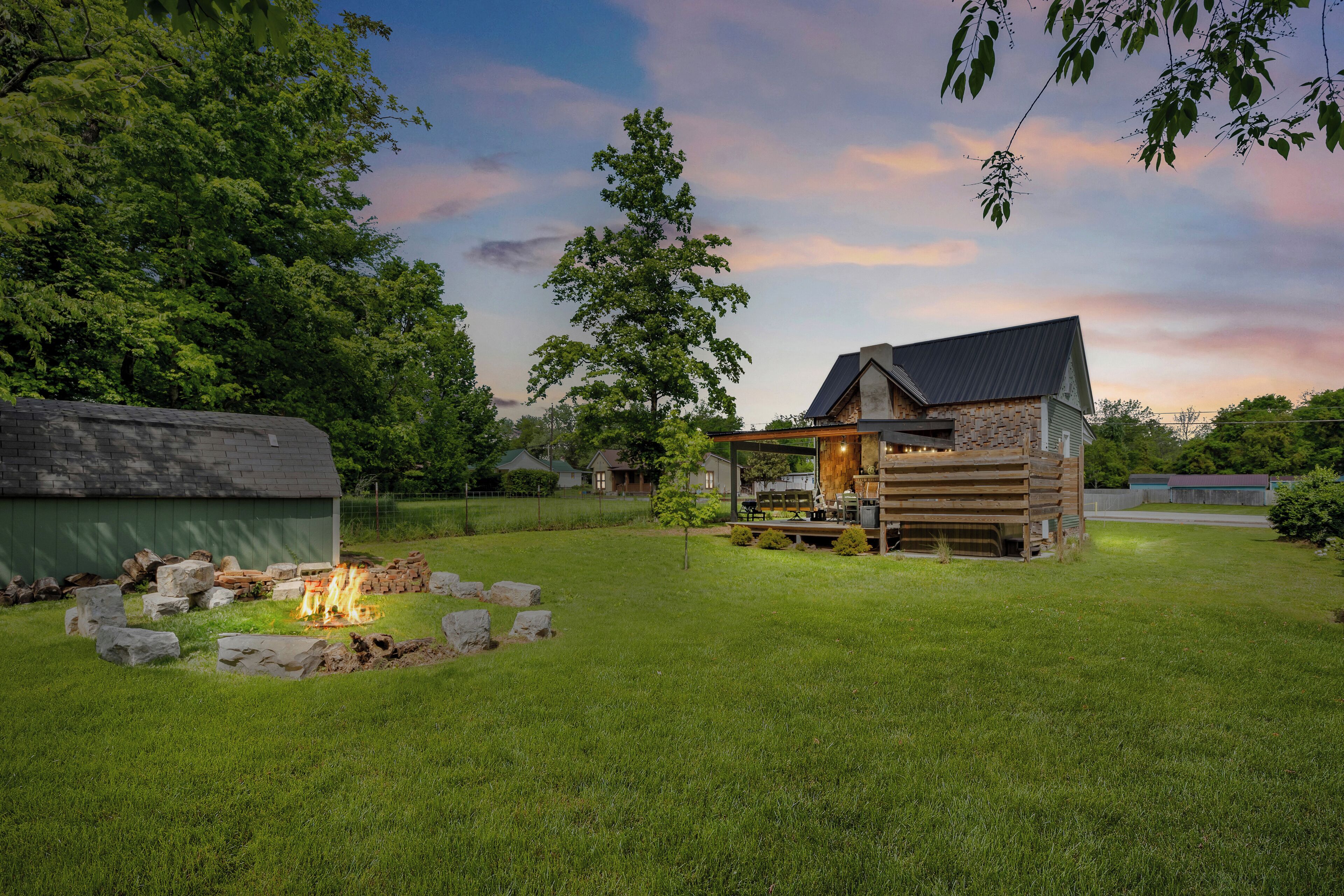 A cabin with a fire pit surrounded by rocks, a covered deck, and a stone exterior.