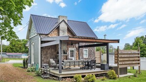 A two-story house with a covered patio, outdoor seating, and a fireplace.