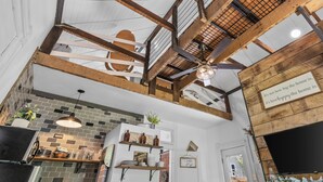 A kitchen with exposed wooden beams, a brick backsplash, and a ceiling fan.
